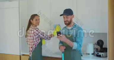 男人和女人<strong>作为</strong>一名职业清洁工，穿着制服，在厨房休息时和电话站在一起。